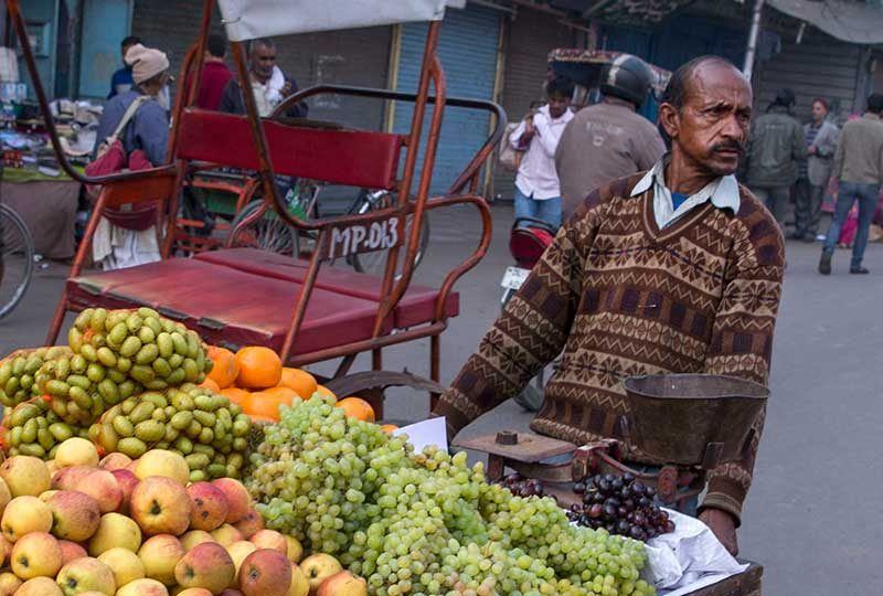 man walking with a fruit cart on an urban street